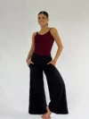 Modelo vestindo calça pantalona preta com bolsos e caimento amplo, ideal para dança e uso casual