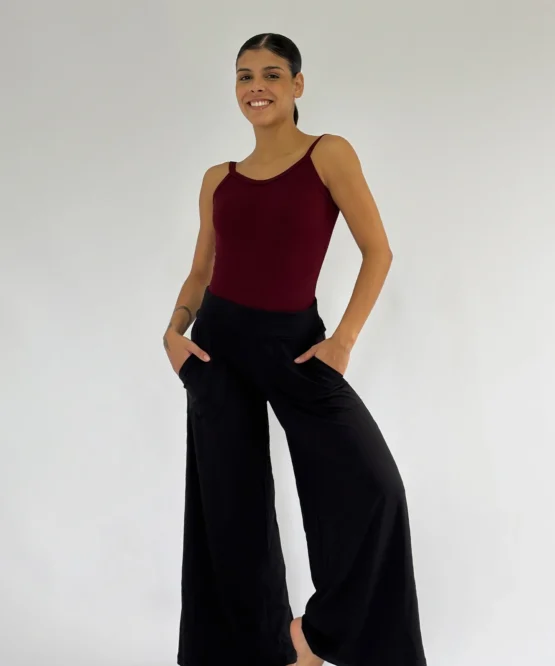 Modelo vestindo calça pantalona preta com bolsos e caimento amplo, ideal para dança e uso casual