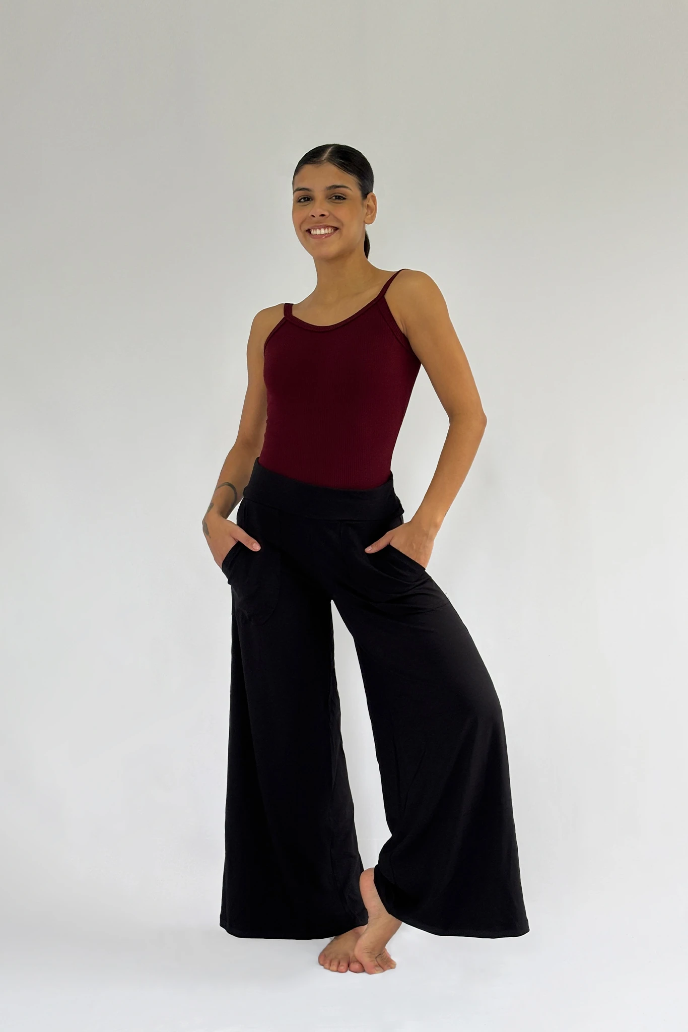 Modelo vestindo calça pantalona preta com bolsos e caimento amplo, ideal para dança e uso casual