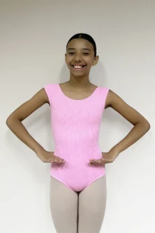 Jovem bailarina sorridente em pose de preparação vestindo o Collant Aninha Infantil Candy rosa, de tecido canelado, em pose de dança com as mãos no quadril.