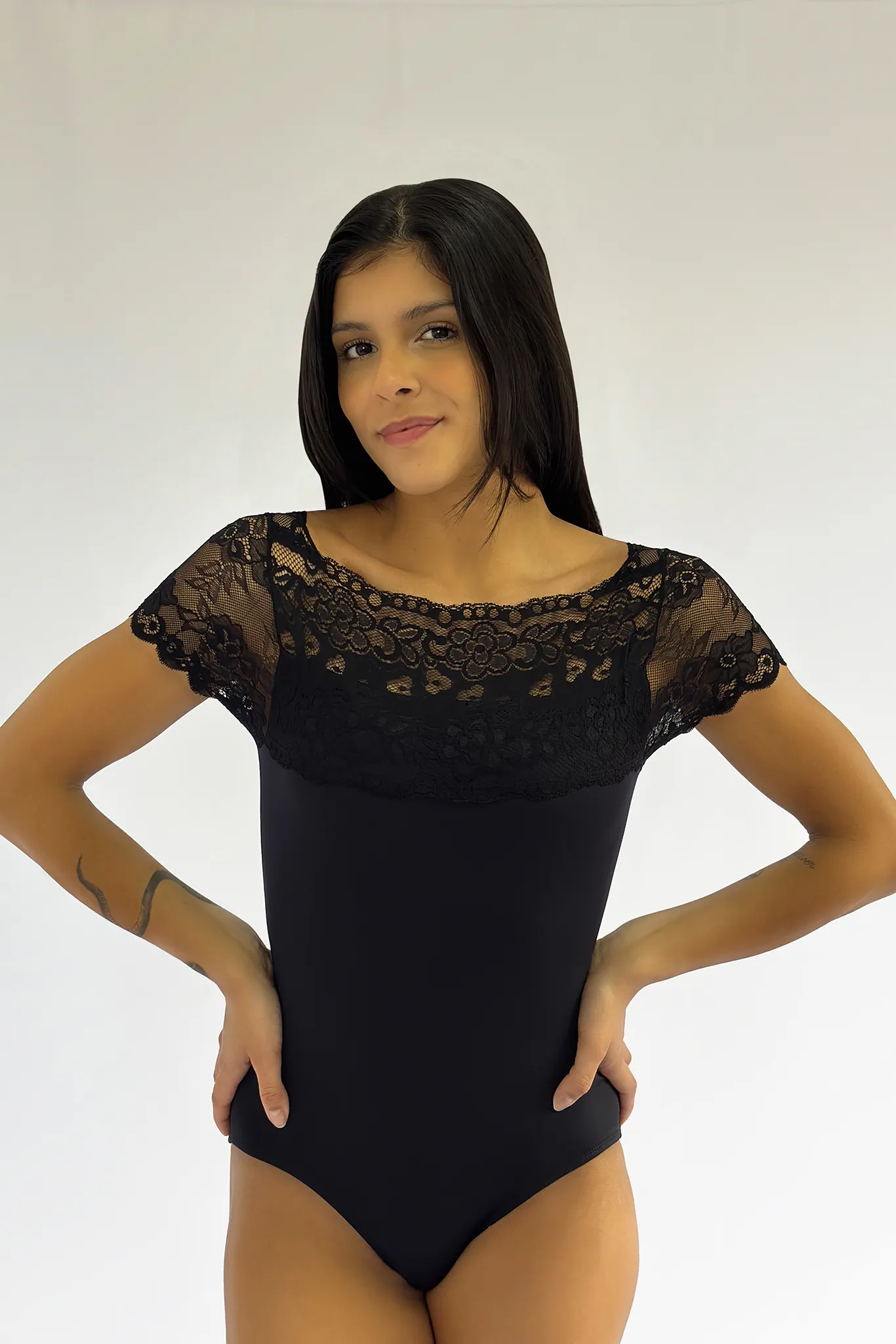 Bailarina de frente usando o Collant Lucia Caliman 01.062 preto, com detalhe de renda nos ombros e decote canoa.