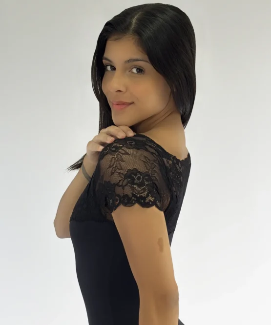 Vista lateral/costas de uma bailarina com o Collant 01.062 preto, destacando o design da manga de renda no ombro.