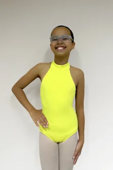 Jovem bailarina de frente, com a mão direita na cintura usando o Collant Infantil Frente Única na cor Amarelo Candy da Lucia Caliman.