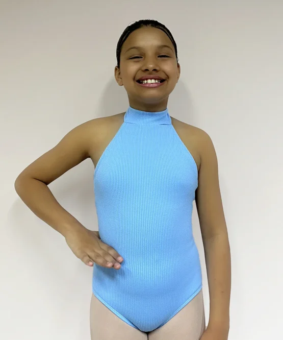 Vista frontal de uma jovem bailarina com a mão direita na cintura, vestindo o Collant Infantil Frente Única Azul Candy da Lucia Caliman