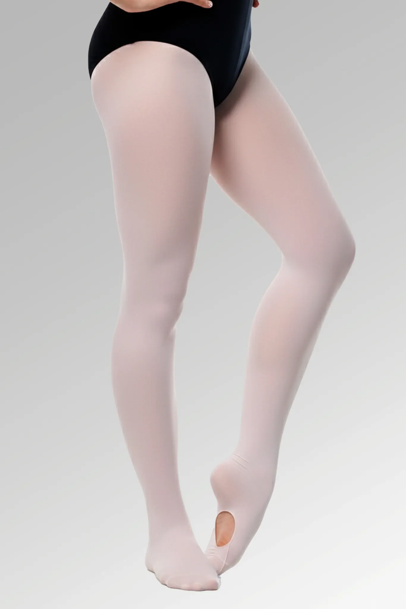 Bailarina infantil usando a Meia Supplex Conversível rosa da Lucia Caliman, mostrando a abertura funcional no pé em uma pose delicada de ballet.