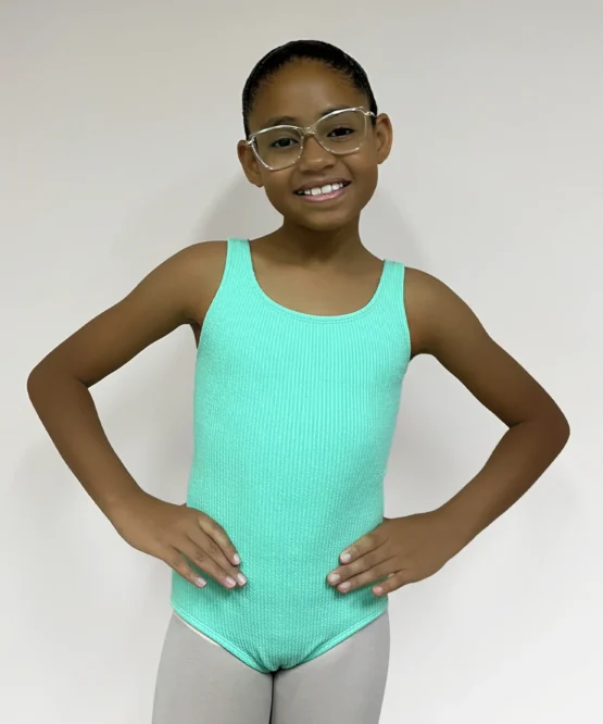 Jovem dançarina usando o Collant Infantil Quadrado Verde Candy da Lucia Caliman, visto de frente em fundo neutro.