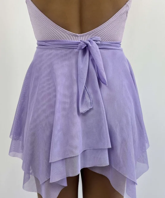 Bailarina de costas vestindo a Saia Odette lilás em tule de lycra da Lucia Caliman, detalhe lateral mostrando o caimento fluido sobre o collant.