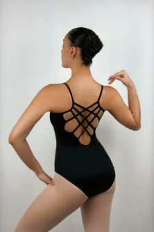 Foto da bailarina de costas usando o Collant Alça Trançada preto da Lucia Caliman, exibindo o detalhe geométrico de múltiplas alças cruzadas nas costas abertas, em uma pose elegante com as mãos na cintura.
