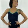 Modelo de pele negra e cabelos cacheados sorrindo, usando o Collant Ana Paula azul marinho com alças e viés verde bandeira, em pose frontal com as mãos na cintura.