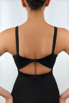Detalhe da Bailarina de costas vestindo o Collant Costas Torcida preto da Lucia Caliman, exibindo o detalhe de tecido torcido no centro das costas nuas e as alças largas, em uma pose com as mãos na cintura.