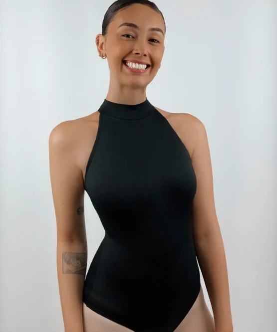 Bailarina de frente sorrindo e usando o Collant Frente Única Três Tiras preto da Lucia Caliman, destacando a gola alta elegante e o design sem mangas que valoriza os ombros.