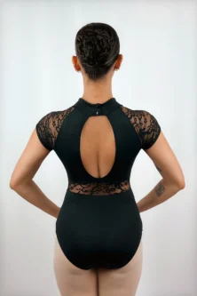 Bailarina de costas exibindo o Collant Manga Japonesa preto da Lucia Caliman. O foco está no elegante recorte oval nas costas nuas, nas mangas em renda floral, no fechamento por dois botões na nuca e no detalhe rendado que contorna a região lombar.