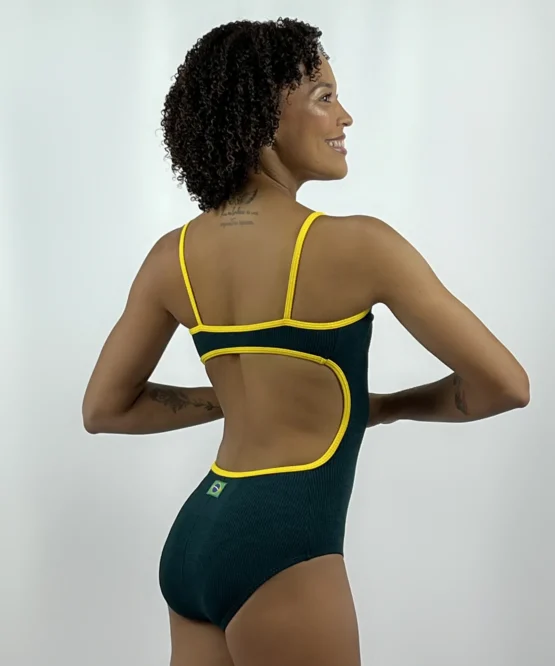 Vista posterior da modelo usando o Collant Marta verde e amarelo da Lucia Caliman, destacando o recorte oval nas costas, as alças finas e o detalhe da bandeira do Brasil.