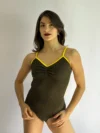 Modelo bailarina vestindo o Collant Marta verde com detalhes em amarelo da Lucia Caliman, com foco no decote em V e franzido frontal.