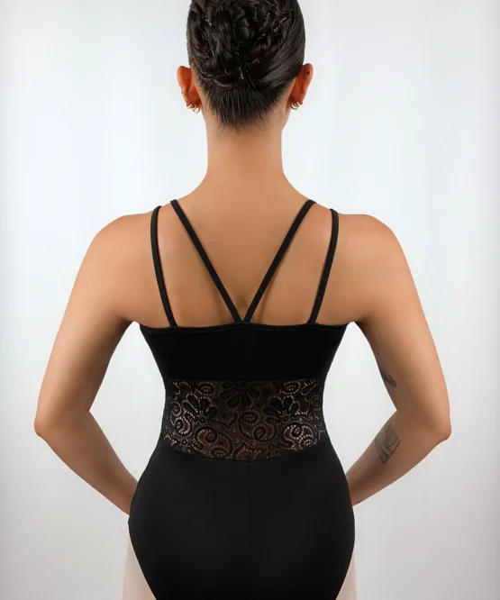 Bailarina usando o Collant Recorte Cintura preto da Lucia Caliman em vista posterior direta, com as mãos na cintura, destacando a simetria das alças finas nas costas e a delicadeza da renda transparente.
