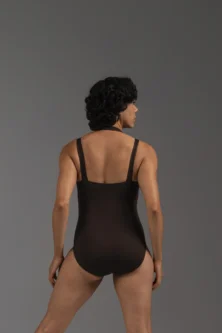 Bailarina de costas usando o Collant Duna na cor Café da Lucia Caliman. A foto destaca o decote quadrado, as alças firmes e a modelagem clássica que oferece suporte e segurança.