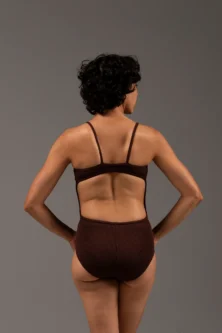 Bailarina de costas com o Collant Marta marrom da Lucia Caliman. Peça com modelagem anatômica, evidenciando o conforto e a liberdade de movimento nos braços e ombros.