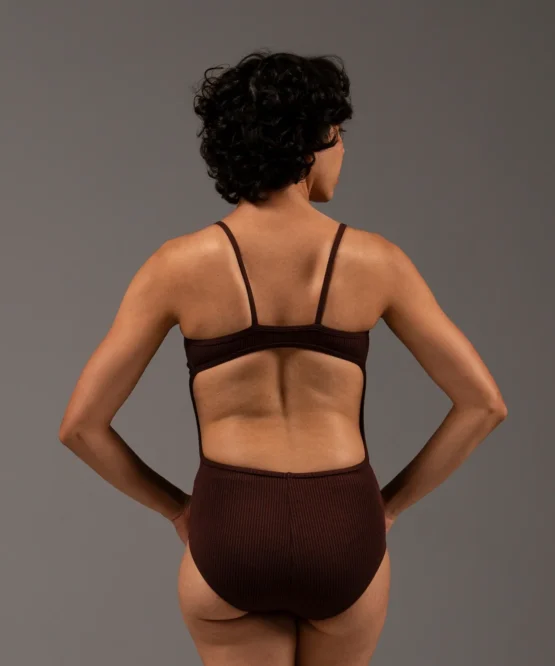 Bailarina de costas com o Collant Marta marrom da Lucia Caliman. Peça com modelagem anatômica, evidenciando o conforto e a liberdade de movimento nos braços e ombros.