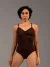 Bailarina de frente com o Collant Marta marrom da Lucia Caliman. Peça com modelagem anatômica, evidenciando o conforto e a liberdade de movimento nos braços e ombros.