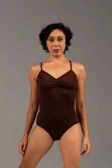 Bailarina de frente com o Collant Marta marrom da Lucia Caliman. Peça com modelagem anatômica, evidenciando o conforto e a liberdade de movimento nos braços e ombros.