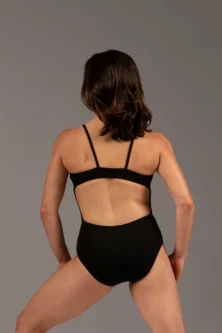 Bailarina de costas usando o Collant Marta preto da Lucia Caliman. A peça possui textura canelada, decote em V franzido no busto e alças finas, transmitindo segurança e elegância.