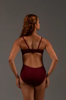 Bailarina de costas vestindo o Collant Marta vinho da Lucia Caliman. A imagem destaca o caimento perfeito da malha canelada e o recorte vazado nas costas com faixa de sustentação.