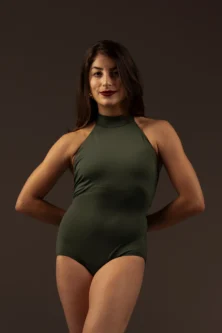 Bailarina com o Collant Frente Única verde da Lucia Caliman, vista de frente com os braços para trás, demonstrando o ajuste perfeito da peça ao corpo.